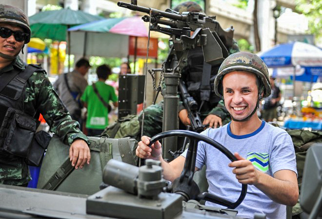 Иностранный турист в каске сидит в военной машине армии Таиланда в Бангкоке после объявления военного положения 20 мая 2014 года. В стране обострился политический кризис, который в течение 6 месяцев унёс жизни не менее 28 человек. Фото: Rufus Cox/Getty Images | Epoch Times Россия