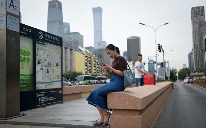 Женщина с мобильным телефоном у входа в подземный переход в Пекине, 18 сентября 2018 года. /Wang Zhao / AFP / Getty Images | Epoch Times Россия