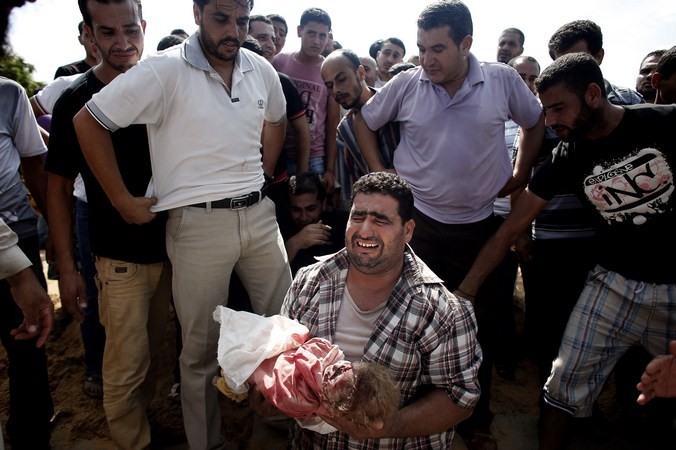 Палестинец оплакивает ребёнка, одного из восьми членов его семьи, убитых за одну ночь во время израильского обстрела, Сектор Газа, 19 июля, 2014 год. Фото:  THOMAS COEX / AFP / Getty Images | Epoch Times Россия