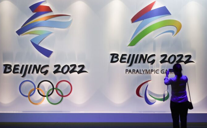 Посетитель фотографирует логотипы предстоящих зимних Олимпийских и Паралимпийских игр в Пекине 2022 года на Пекинской олимпийской выставке, 8 августа 2018 года. WANG ZHAO/AFP via Getty Images | Epoch Times Россия