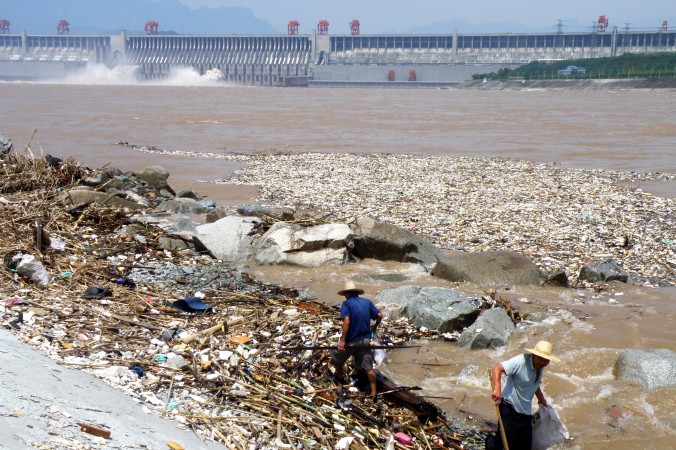 Двое рабочих убирают мусор вдоль берега реки Янцзы вблизи дамбы Трёх ущелий в Ичане, провинция Хубэй, 1 августа 2010 г. Фото: STR/AFP/Getty Images | Epoch Times Россия