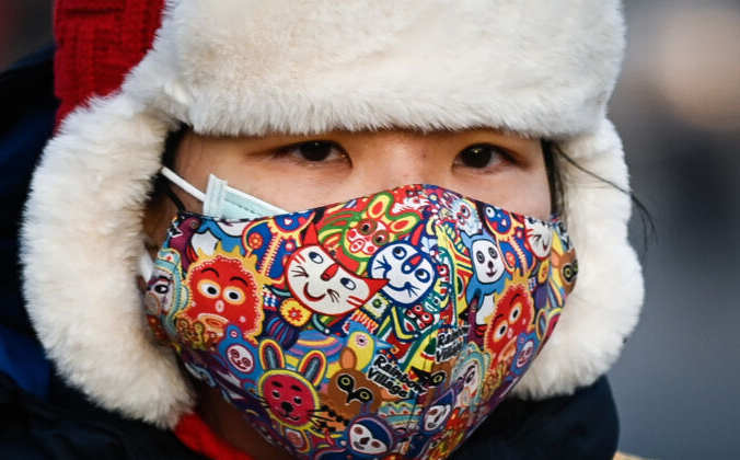 Женщина в маске едет на электрическом велосипеде по улице Пекина 10 декабря 2020 года. WANG ZHAO/AFP via Getty Images | Epoch Times Россия