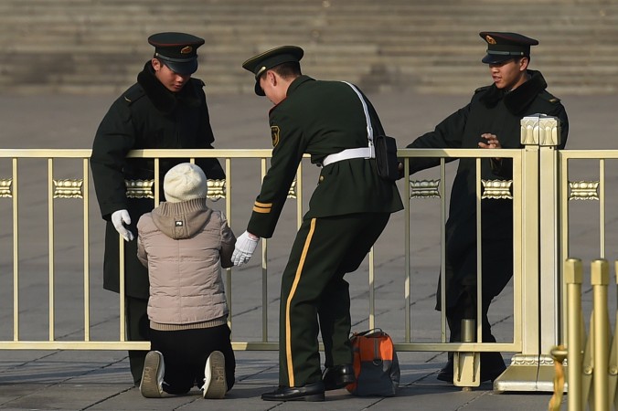 Военизированная полиция останавливает женщину, которая протестует на коленях у Дома народных собраний в Пекине 13 марта 2015 г. Фото: GREG BAKER/AFP/Getty Images | Epoch Times Россия