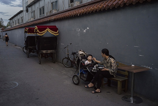 Китаянка кормит сына в ресторане в хутуне ― традиционном закрытом жилом районе 12 июня 2015 г., Пекин, Китай. Фото: Kevin Frayer/Getty Images | Epoch Times Россия
