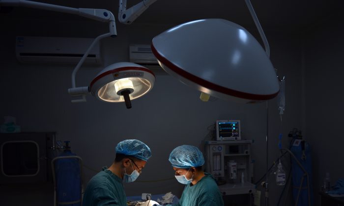 На этой фотографии, сделанной 9 августа 2013 года, показан пластический хирург Ван Сюмин (слева), выполняющий «особую» операцию на носу пациенту в своей клинике в городе Чунцин на юго-западе Китая. (Питер Паркс / AFP / Getty Images) | Epoch Times Россия