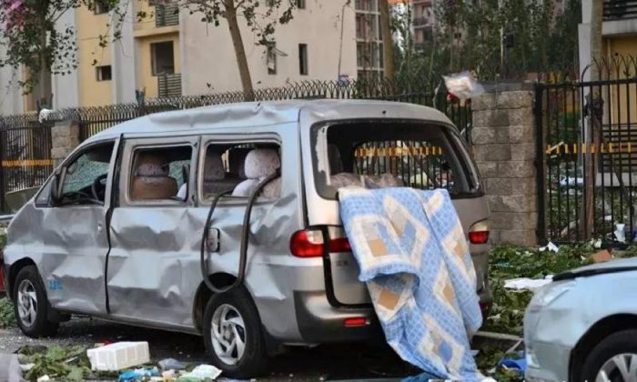 Поврежденная машина возле места взрыва в Тяньцзине, Китай, 13 августа 2015 года, захваченная журналистом, пробирающимся через блокаду полиции. (Хэ Сяосинь / WeChat) | Epoch Times Россия