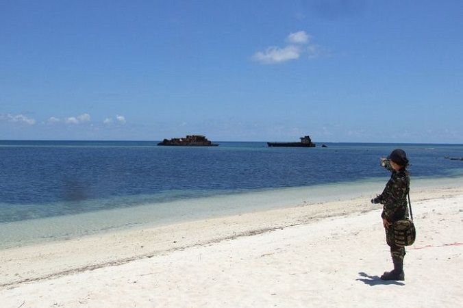 Военнослужащий стоит на пляже острова Тхиту, на котором находится небольшой филиппинский город, а также взлетно-посадочная полоса, используемая для гражданских и военных полётов на спорные острова Спратли в Южно-Китайском море. Июнь, 2014 год. Фото: STR/AFP/Getty Images | Epoch Times Россия
