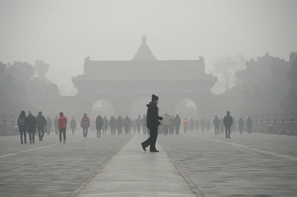 Пожилой мужчина идет перед группой людей во время сильного смога. 20 декабря 2016 год, Пекин. Фото / Wang Zhao/AFP/Getty Images | Epoch Times Россия