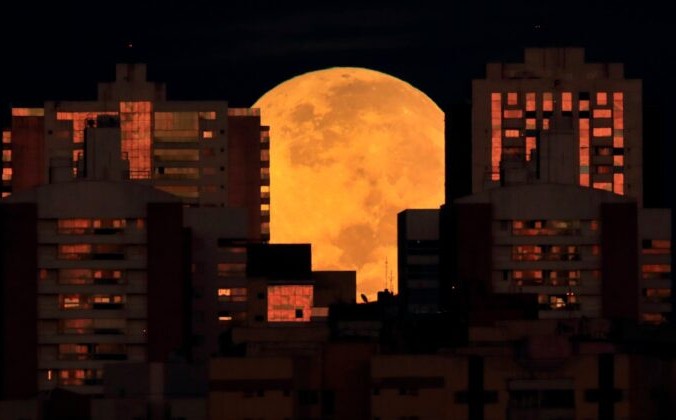 Луна частично закрыта зданиями в Бразилиа, Бразилия, в начале полного лунного затмения 26 мая 2021 года. (Eraldo Peres / AP Photo) | Epoch Times Россия