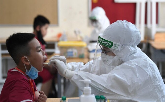 Медицинский работник в защитном костюме (PPE) берёт мазок на COVID-19 у ученика частной школы Vinschool в Ханое, Вьетнам, 22 мая 2021 г. Nhac Nguyen / AFP via Getty Images | Epoch Times Россия