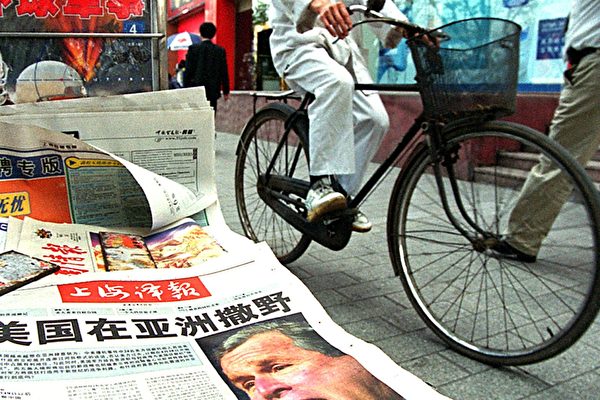Житель Шанхая проезжает мимо китайской газеты с изображением президента США Джорджа Буша и заголовоком «Соединённые Штаты действуют безумно в Азии», Шанхай, 19 апреля 2001 года. LIU JIN/AFP/Getty Images | Epoch Times Россия