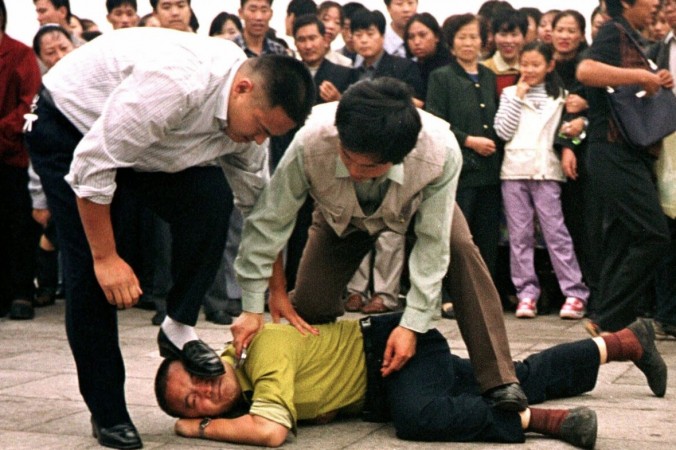 Полиция задерживает последователя Фалуньгун на площади Тяньаньмэнь во время протеста, в то время как толпа наблюдает за происходящим в Пекине 1 октября 2000 года. (Chien-min Chung/AP Photo) | Epoch Times Россия