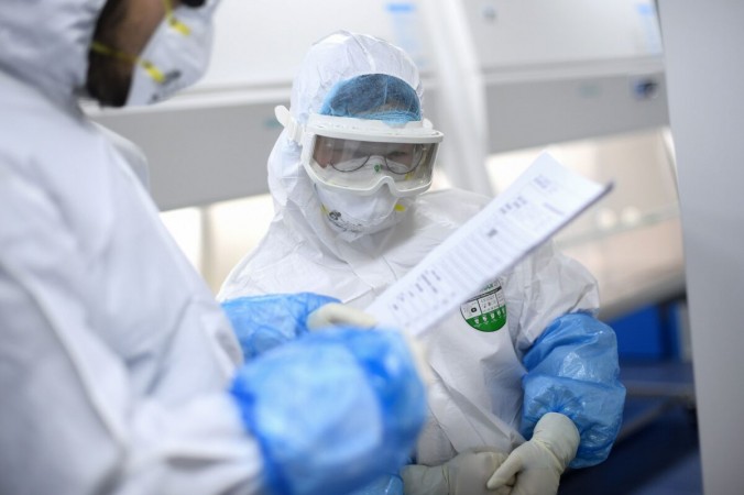Лаборанты во время работы над образцами для тестирования на COVID-19 в лаборатории BGI в Ухане, Китай, 6 февраля 2020 г. (STR / AFP через Getty Images) | Epoch Times Россия