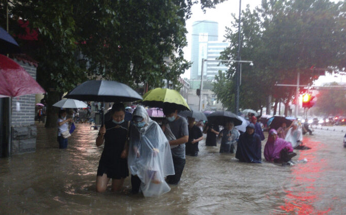 Люди движутся через паводковые воды после сильного ливня в городе Чжэнчжоу провинции Хэнань в центральном Китае, 20 июля 2021 г. Chinatopix Via AP | Epoch Times Россия