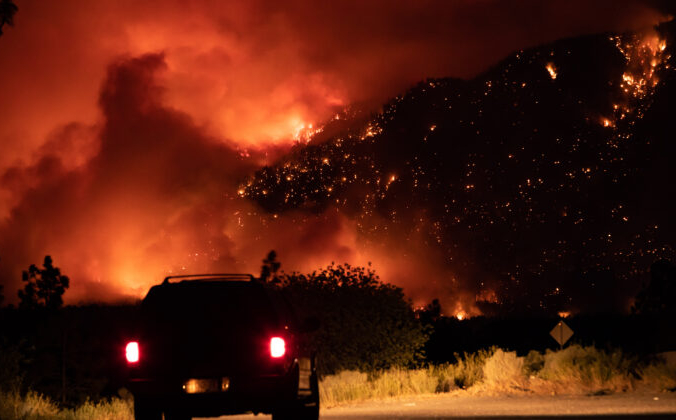 Автомобилист наблюдает с выезда на Трансканадское шоссе, как лесной пожар охватил склон горы в Литтоне, Британская Колумбия, 1 июля 2021 г. Фото: The Canadian Press / Darryl Dyck | Epoch Times Россия