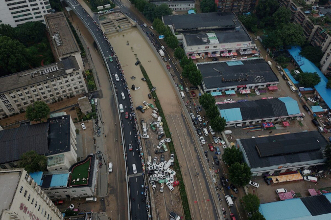 Автомобили, стоящие в паводковых водах у входа в туннель скоростной автомагистрали Цзингуан после проливных дождей, обрушившихся на город Чжэнчжоу в центральной китайской провинции Хэнань 22 июля 2021 года. (Noel Celis / AFP) | Epoch Times Россия