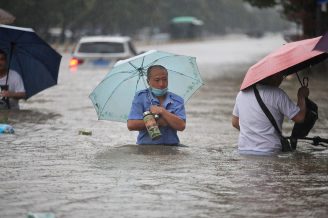 Жители идут по затопленной дороге во время проливных дождей в Чжэнчжоу, провинция Хэнань, Китай, 20 июля 2021 г. (China Daily via Reuters) | Epoch Times Россия