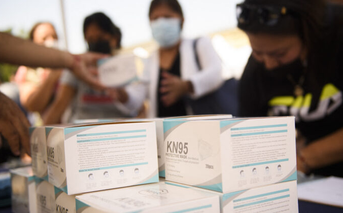 Люди получают коробки с масками KN95 во время школьного мероприятия в Лос-Анджелесе, штат Калифорния, 7 августа, 2021 г. Patrick T. Fallon/AFP via Getty Images | Epoch Times Россия