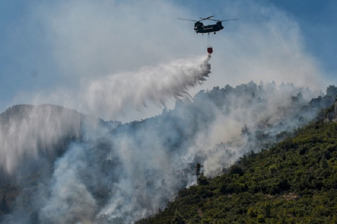 Вертолет сбрасывает воду на горящий лес возле Малакасы, на севере от Афин 7 августа 2021 года. Photo de Louisa GOULIAMAKI / AFP via Getty Images. | Epoch Times Россия