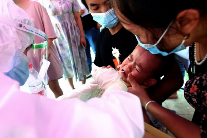 Медицинский работник берет образцы мазков у ребенка во время массового тестирования на вирус КПК в жилом квартале в Ухане, провинция Хубэй, Китай, 3 августа 2021 г. (Chinatopix via AP) | Epoch Times Россия