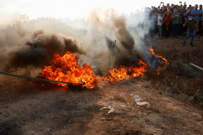 Протестующие подожгли покрышку возле забора на границе сектора Газа с Израилем во время акции протеста 21 августа 2021 г. (Adel Hana/AP Photo) | Epoch Times Россия