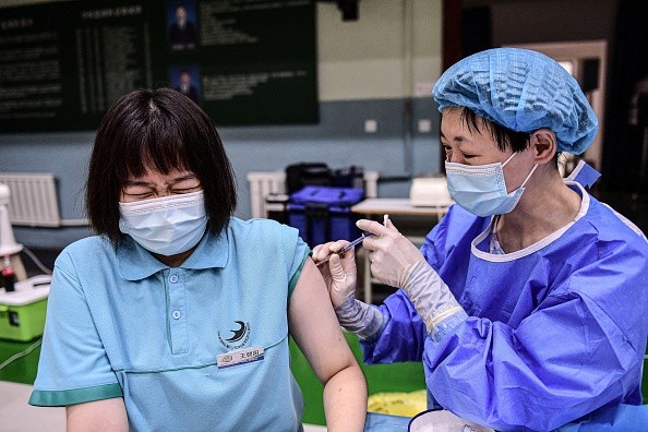 Школьница (слева) реагирует на прививку вакцины Синофарм от COVID-19 в средней школе в Шэньяне, на северо-востоке китайской провинции Ляонин, 28 июля 2021 г. STR / AFP via Getty Images | Epoch Times Россия