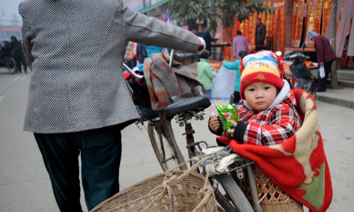 Ребёнок сидит в корзине по пути домой после покупок на весеннем фестивале в Чэнду, провинция Сычуань, Китай, 16 января 2009 г. China Photos / Getty Images | Epoch Times Россия