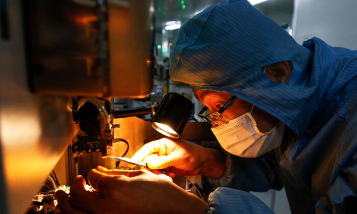 Китайский сотрудник в маске и защитном костюме работает на линии по производству смарт-чипов в округе Сихонг в восточной провинции Китая Цзянсу 16 февраля 2020 г. (STR / AFP) | Epoch Times Россия