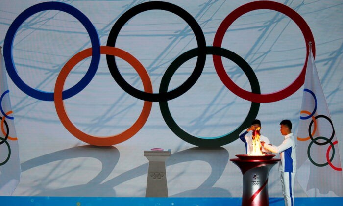 Участники переносят олимпийский огонь из чаши на церемонии приветствия огня на зимних Олимпийских играх 2022 года в Пекине, Китай, 20 октября 2021 г. Tingshu Wang / Reuters | Epoch Times Россия