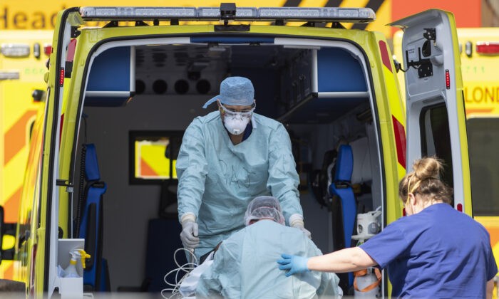 Сотрудники Национальной службы здравоохранения забирают пациента из машины скорой помощи у больницы Святого Томаса в Лондоне, 10 апреля 2020 г. (Justin Setterfield/Getty Images) | Epoch Times Россия