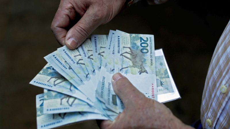 Мужчина держит банкноты номиналом 200 реалов после того, как Центробанк Бразилии выпустил их в Бразилиа 2 сентября 2020 г. (Sergio Lima/AFP via Getty Images) | Epoch Times Россия