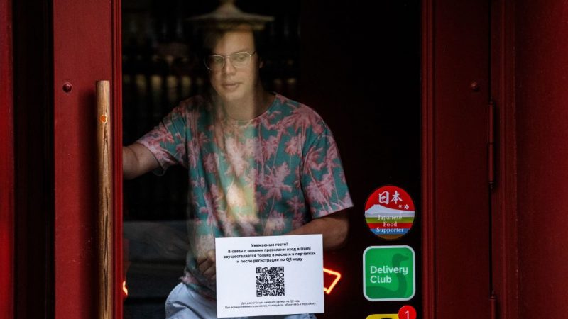 Мужчина выходит из ресторана с табличкой на двери, указывающей на то, что гости должны сначала зарегистрироваться в ресторане с помощью QR-кода, прежде чем смогут занять место. Москва,  22 июня 2021 года. DIMITAR DILKOFF/AFP via Getty Images  | Epoch Times Россия