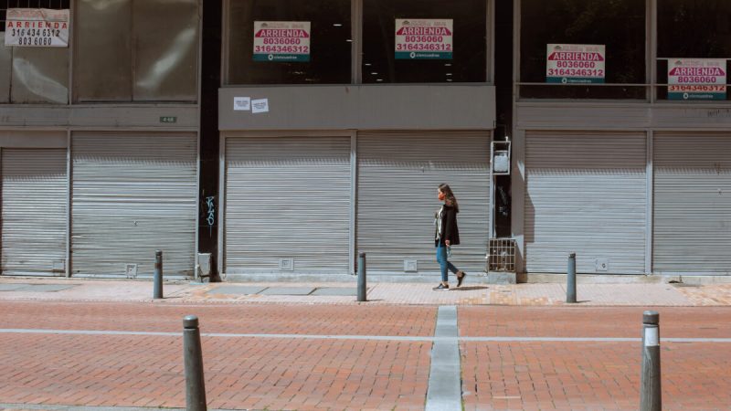 Пешеход идёт мимо пустых окон бизнес-центра с указателями аренды в Боготе, Колумбия, 15 октября 2021 г. (Alejandro Gomez / The Epoch Times) | Epoch Times Россия