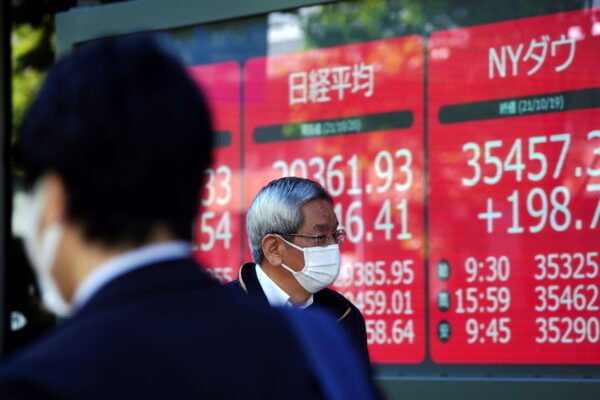 Мужчина в защитной маске возле электронной биржи, на которой видны японский Nikkei 225 © и индексы New York Dow в компании ценных бумаг в Токио, Япония, 20 октября 2021 г. (Eugene Hoshiko / AP Photo) | Epoch Times Россия