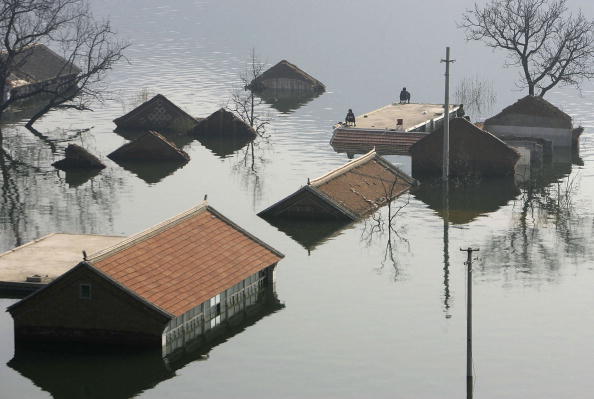 JIXIAN COUNTY, CHINA - OCTOBER 1: (CHINA OUT) Tourists fish on a roof of a submerged house at the Huanxiu Lake on October 1, 2006 in Jixian County of Tianjin Municipality, China. A village was submerged earlier this year in order to enlarge the artificial Huanxiu Lake for developing local tour business and promoting Huanxiu Villas. Tianjin municipality suffers from serious water shortages and experiences earth reduction which affected more than 60 percent of its total area, according to state media. (Photo by China Photos/Getty Images)