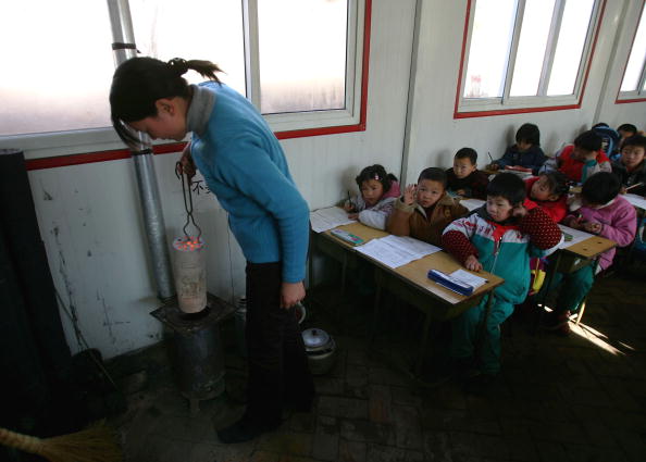 Учитель готовит печь для обогрева класса в одной из крупнейших школ для детей-мигрантов в Пекине, Китай, 28 декабря 2004 г. (Cancan Chu/Getty Images)  | Epoch Times Россия