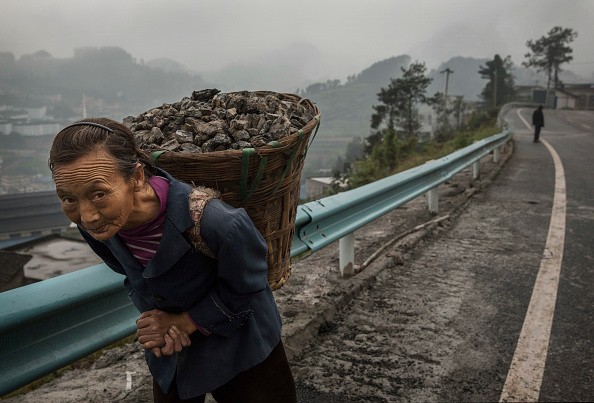 Женщина несёт уголь по мосту над рекой Чишуй в Маотай, провинция Гуйчжоу, Китай, 21 сентября 2016 г. (Kevin Frayer/Getty Images)