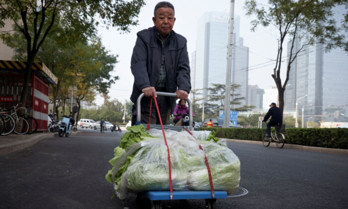 Мужчина перевозит капусту на тележке после того, как купил её в уличном ларьке в Пекине, Китай, 4 ноября 2021 г. REUTERS/Thomas Peter | Epoch Times Россия
