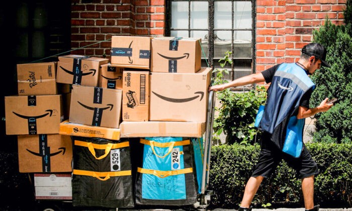 Сотрудник службы доставки Amazon тянет тележку, полную посылок, во время ежегодной акции Prime Day в Нью-Йорке, 21 июня 2021 г. (Brendan McDermid/Reuters) | Epoch Times Россия