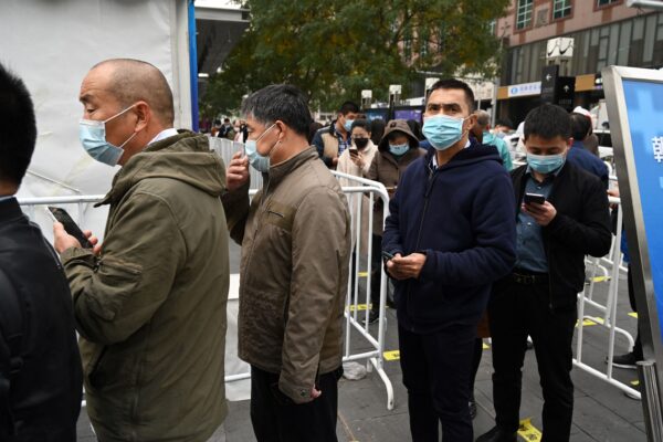 Люди выстраиваются в очередь, чтобы сделать ревакцинацию от COVID-19 в палатке, установленной возле торгового центра в Пекине, 1 ноября 2021 г. (GREG BAKER / AFP via Getty Images)