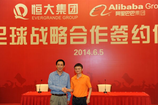 Основатель и председатель Alibaba Group Джек Ма (справа) обменивается рукопожатием с председателем Evergrande Group Сюй Цзяинем во время церемонии подписания соглашения между Alibaba Group и Evergrande Group относительно покупки Alibaba 50% акций Guangzhou Evergrande в провинции Гуандун, Китай, 5 июня. 2014 г. VCG/VCG via Getty Image