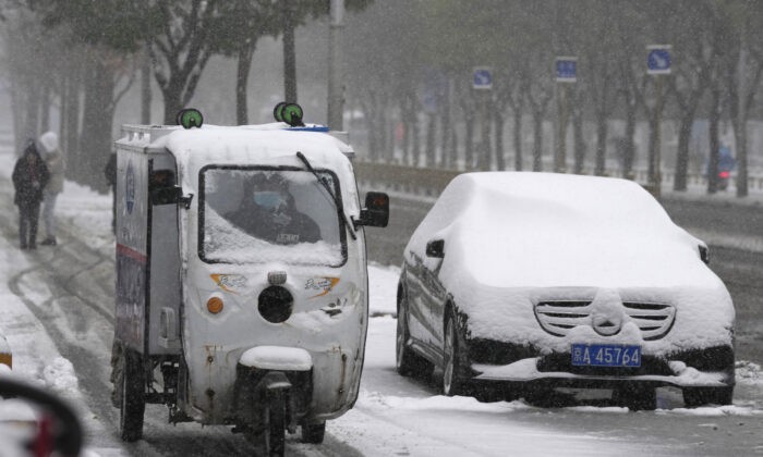 Доставщик проезжает мимо машины, засыпанной снегом в Пекине, Китай, 7 ноября 2021 г. Ng Han Guan/AP Photo | Epoch Times Россия