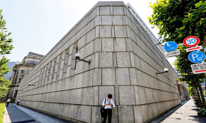 Мужчина смотрит на мобильный телефон перед зданием Банка Японии в Токио, Япония, 16 июня 2017 г. Toru Hanai / Reuters | Epoch Times Россия