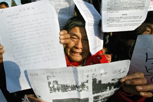 Протестующие показывают свои документы во время митинга против коррупции и взяточничества в преддверии ежегодного национального «юридического дня» в Пекине 3 декабря 2007 г. Teh Eng Koon/AFP via Getty Images