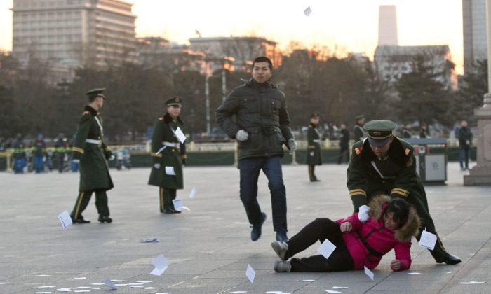 Полицейский толкнул женщину, протестующую против несправедливости в отношении её дела. Женщина бросила листовки, когда её окружила полиция возле столба с государственным флагом на площади Тяньаньмэнь в Пекине 5 марта 2014 г. Alexander F. Yuan/AP Photo | Epoch Times Россия