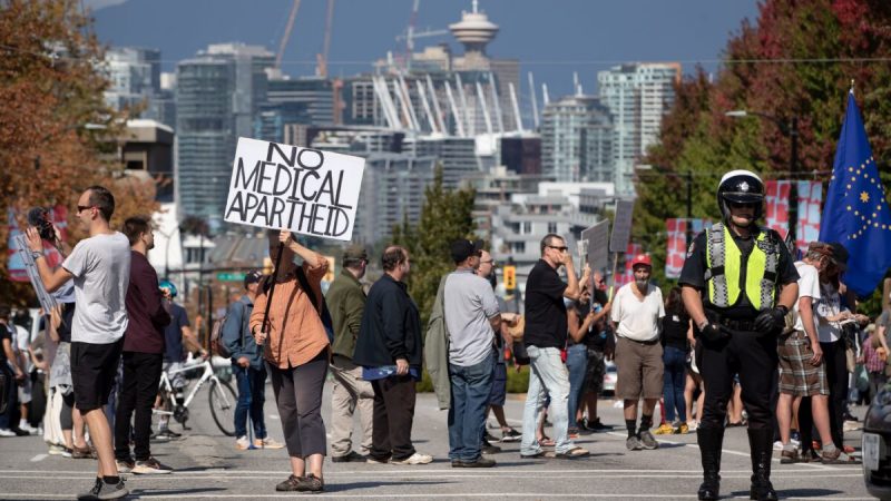 Офицер полиции стоит в стороне во время митинга против обязательной вакцинации от COVID-19 и мер общественного здравоохранения в Ванкувере 8 сентября 2021 г. (The Canadian Press/Darryl Dyck)  | Epoch Times Россия