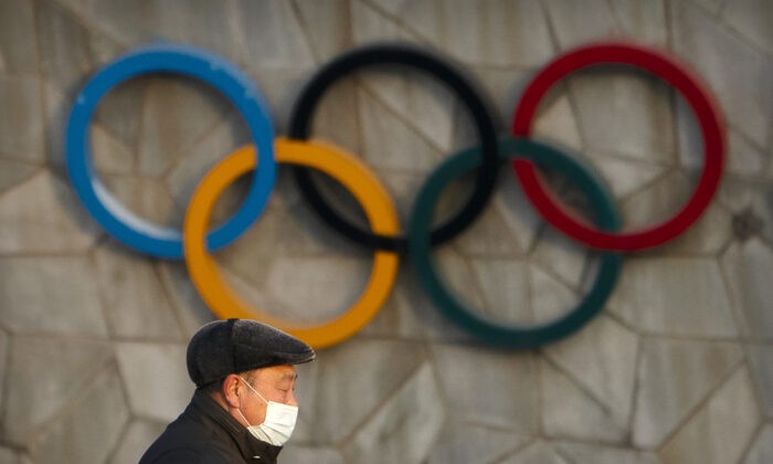 Мужчина на фоне олимпийских колец предстоящих зимних Олимпийских игр 2022 года в Пекине, 2 февраля 2021 года. (Mark Schiefelbein/AP Photo) | Epoch Times Россия