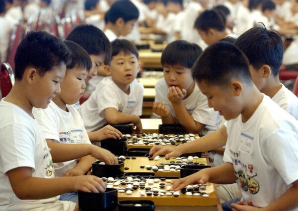 Южнокорейские школьники расставляют белые и чёрные камни во время Всемирного соревнования по игре в го среди учащихся начальных школ, Сеул, 29 июля 2005. (JUNG YEON-JE/AFP via Getty Images)