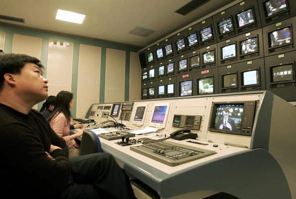 Китайские продюсеры и технические специалисты следят за экранами, пока французский диктор передаёт новости в студии Центрального телевидения Китая (CCTV) в Пекине, 25 ноября 2004 года. (GOH CHAI HIN/AFP/Getty Images) | Epoch Times Россия