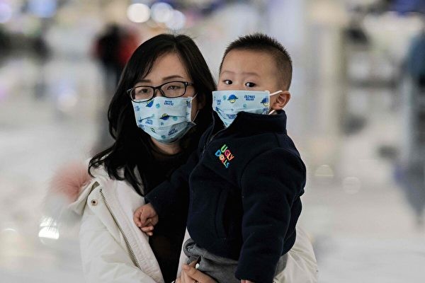 Женщина в маске держит ребёнка, когда она идёт к стойке регистрации в международном аэропорту Дасин в Пекине 21 января 2020 года. (Nicolas Asfouri/AFP via Getty Images)
 | Epoch Times Россия